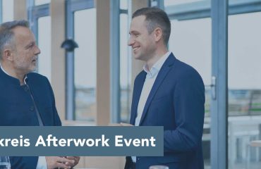 Header_aktivkreis_event_2000x850px Two businesspeople in blue suits chat in a bright, modern office space; overlay reads '1. Aktivkreis Afterwork Event'.